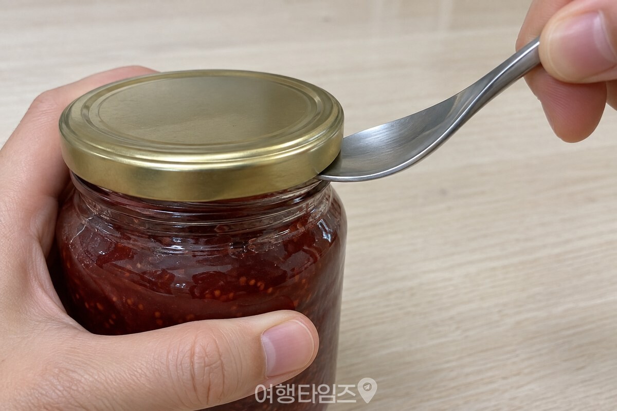 금속 뚜껑 아래 테두리와 유리병 목 사이에 숟가락 끝을 얕게 끼운 모습. / 기사 이해를 돕기 위한 생성형 이미지