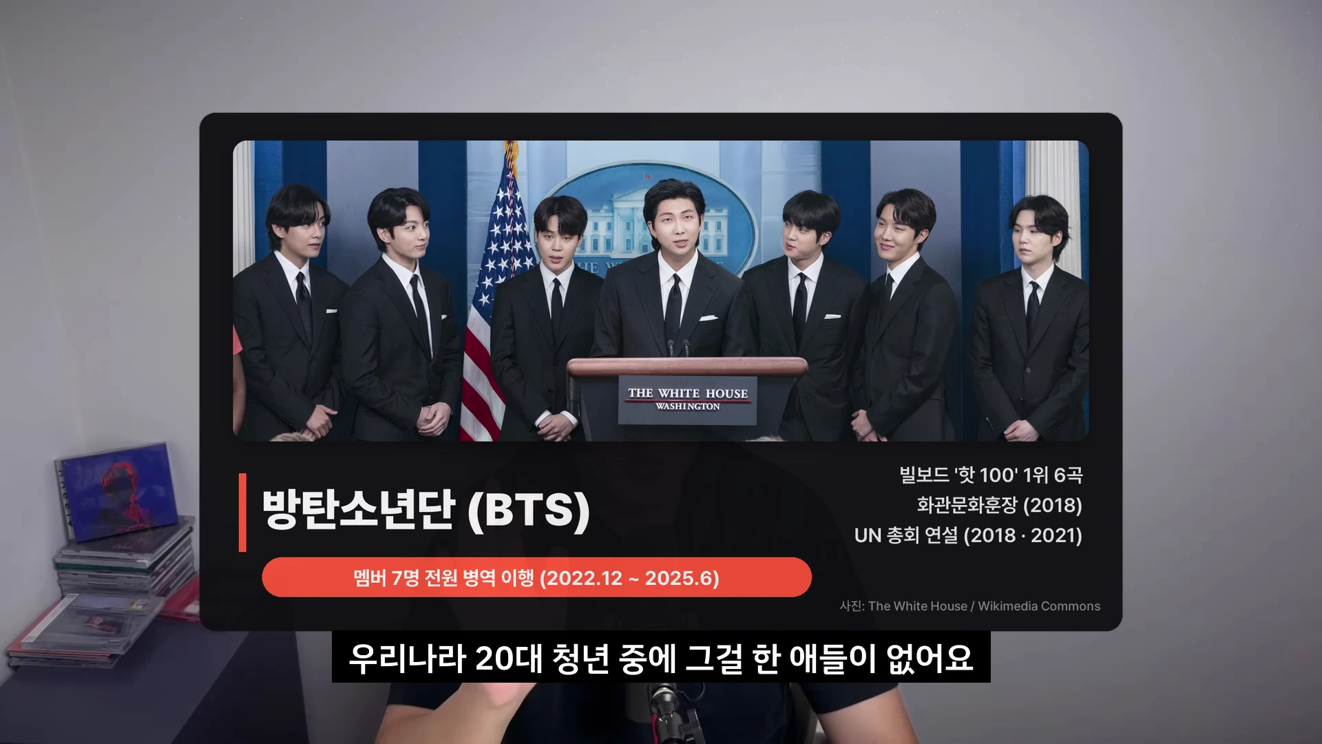 정장을 입은 7명의 방탄소년단 멤버들이 백악관 연단 앞에 서 있는 사진이 삽입된 영상 화면.