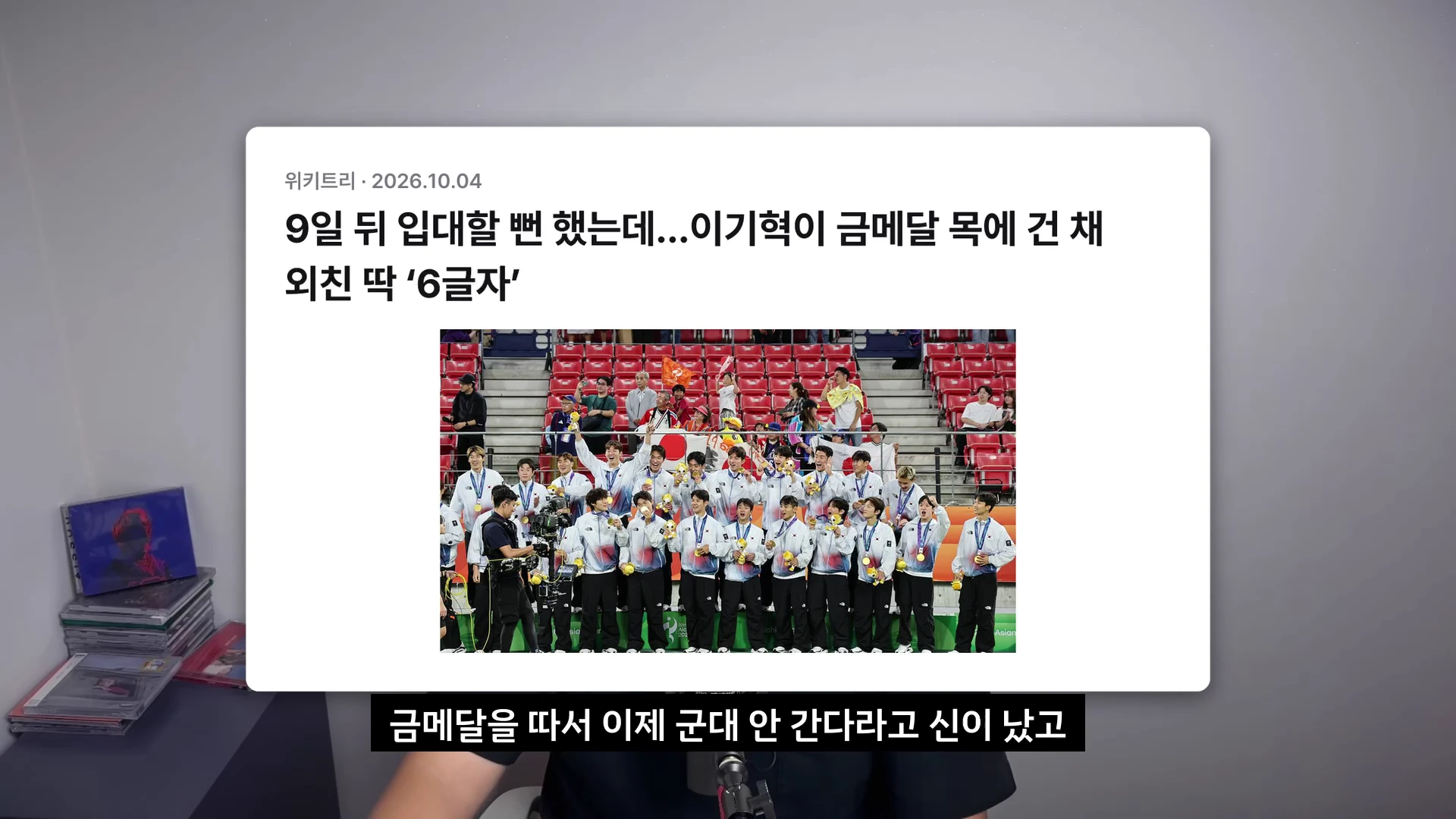 아시안게임 축구 대표팀 선수들이 금메달을 목에 걸고 경기장에서 단체 사진을 촬영하는 모습을 담은 뉴스 기사 스크린샷.