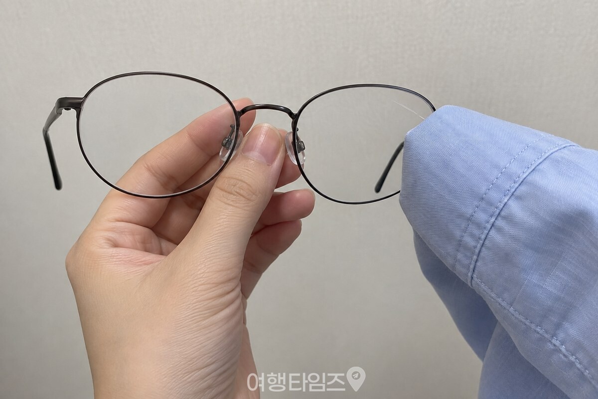 깨끗한 셔츠 소매로 안경 렌즈를 마른 상태에서 문지르려는 가까운 모습. / 기사 이해를 돕기 위한 생성형 이미지