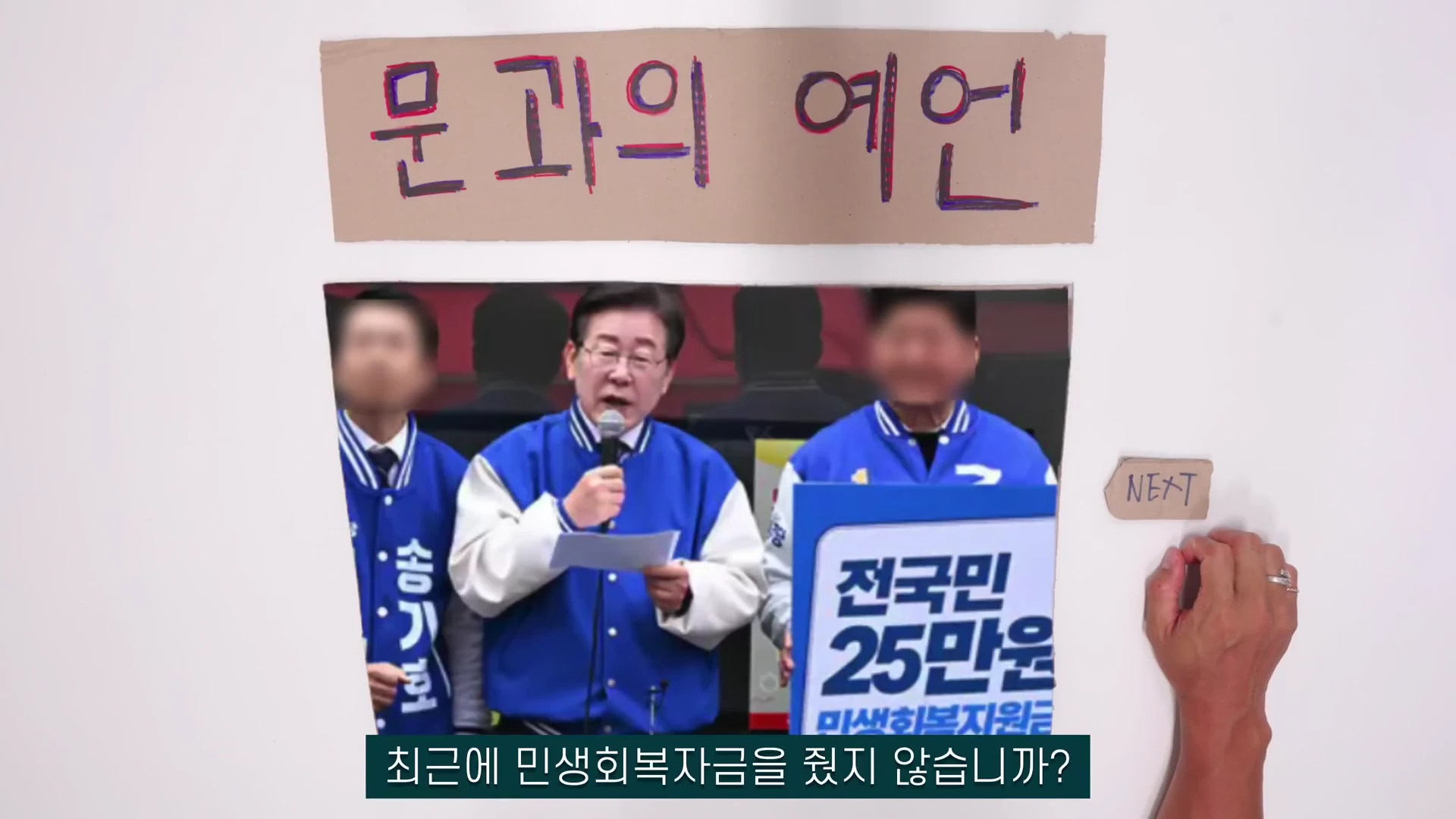 흰 벽에 '문과의 예언'이라는 글씨가 적힌 종이가 붙어 있고, 그 아래에는 파란 재킷을 입은 사람들이 마이크를 잡고 있는 영상 화면이 액자처럼 놓여 있습니다. 오른편에는 'NEXT'라고 적힌 작은 종이를 가리키는 손이 보입니다.