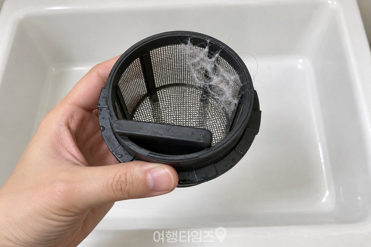세탁기에서 꺼낸 둥근 배수필터의 촘촘한 거름망에 실밥과 머리카락이 걸려 있는 모습. / 기사 이해를 돕기 위한 생성형 이미지