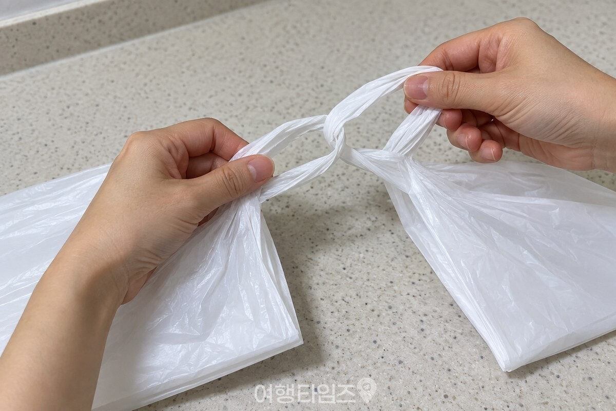 길쭉하게 접은 비닐봉지 두 장의 손잡이를 서로 끼워 연결하는 손. / 기사 이해를 돕기 위한 생성형 이미지