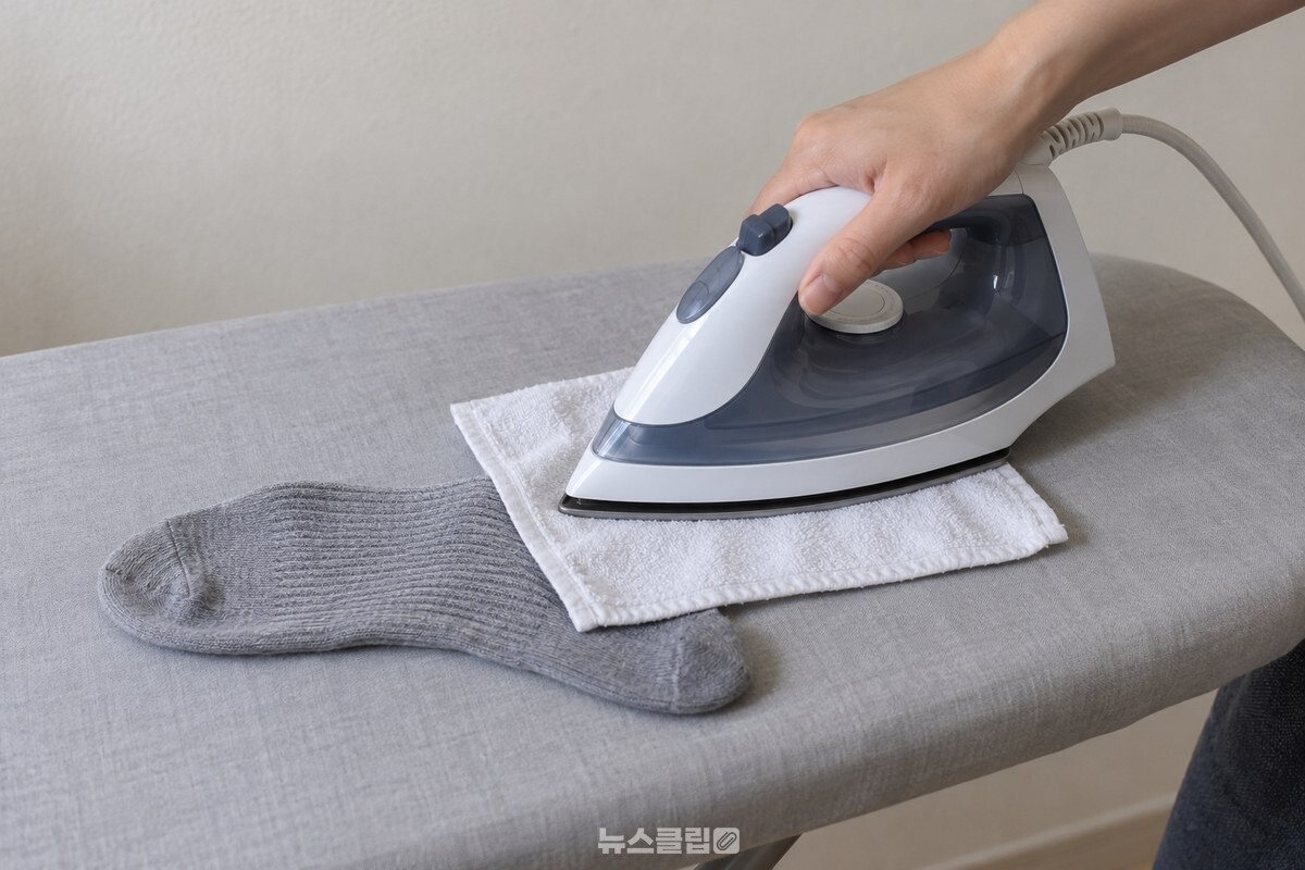 얇은 흰 면수건을 덮은 양말 목 위를 스팀 없이 다리미로 누르는 모습. / 기사 이해를 돕기 위한 생성형 이미지