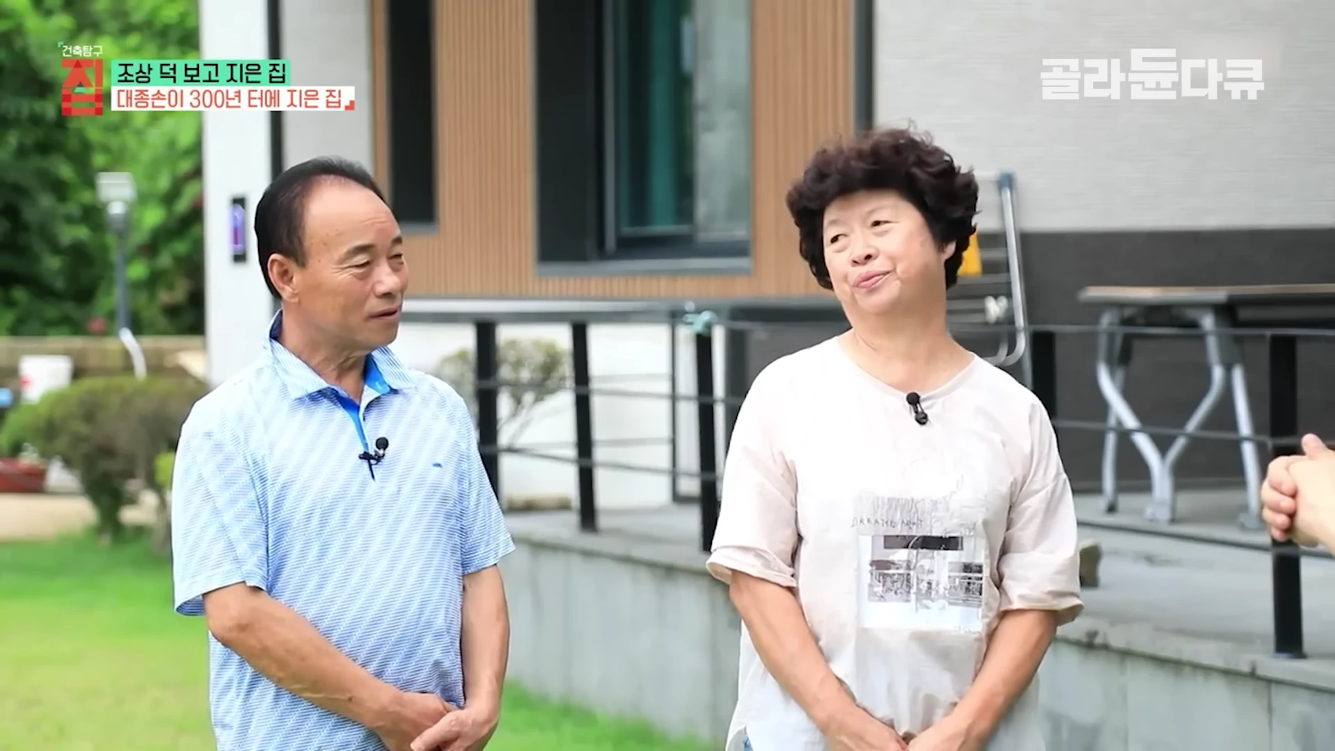 남성과 여성이 새로 지은 현대적인 집 앞 정원에서 대화를 나누고 있는 모습이 담긴 방송 화면