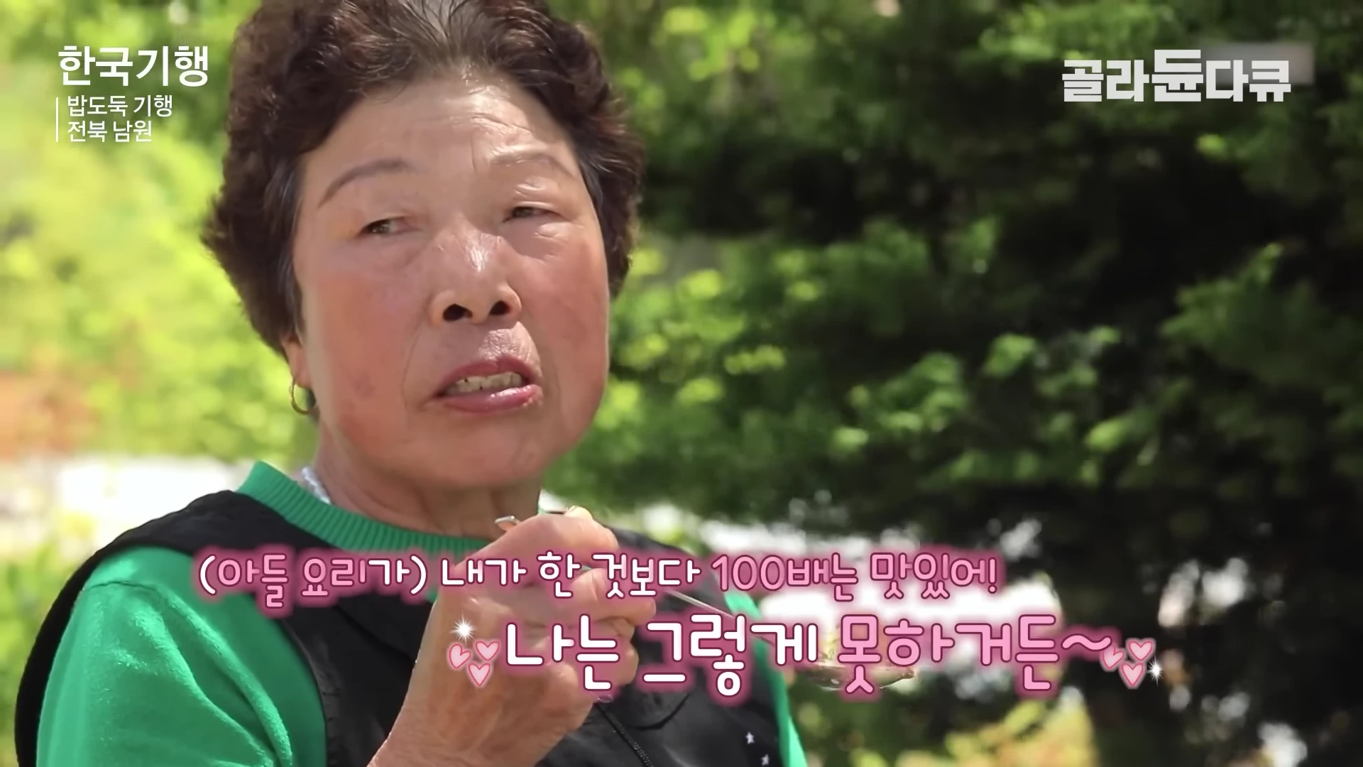 초록색 상의를 입은 중년 여성이 숟가락을 들고 식사를 하며 미소 짓고 있는 모습이 담긴 방송 화면