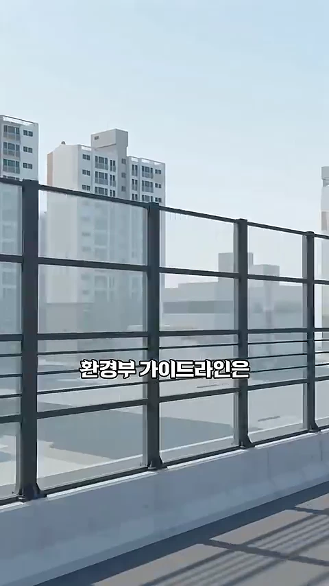 도로변에 설치된 투명 방음벽의 모습. 갈색 프레임이 격자 형태로 나뉘어 있으며 화면 중앙에 '환경부 가이드라인은'이라는 자막이 떠 있습니다.