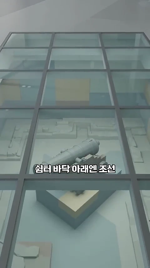 서울시청 지하 군기시 유적 전시실의 유리 바닥 아래로 조선 시대 대포 유물과 발굴된 건축 유구가 전시되어 있는 모습.