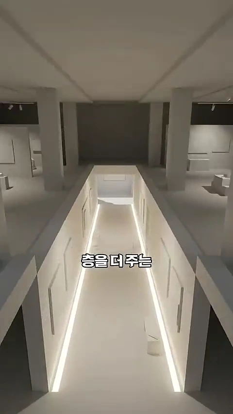 현대적인 화이트 톤의 건물 내부 공간으로, 중앙 통로를 따라 밝은 조명이 설치되어 있고 기둥들이 세워져 있는 모습