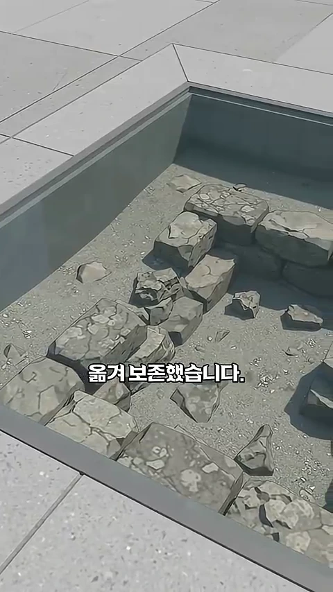 현대식 바닥 타일로 둘러싸인 정사각형의 유리창 아래로 오래된 돌과 흙이 쌓여 있는 유구 터가 들여다보이는 모습입니다.