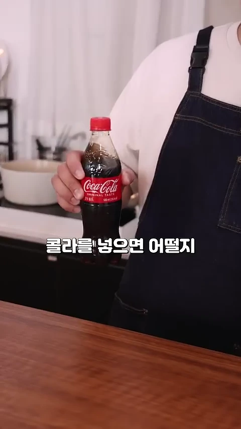앞치마를 입은 사람이 코카콜라 페트병을 들고 있는 모습이며 화면 하단에 콜라를 넣으면 어떨지라는 자막이 떠 있습니다.