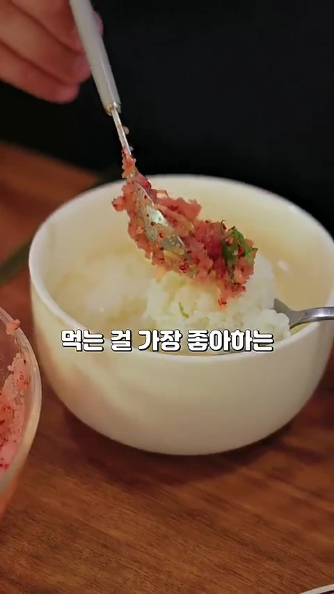 흰 그릇에 담긴 흰 밥 위에 숟가락으로 명란 무침을 올리는 모습이 담긴 근접 촬영 영상 화면