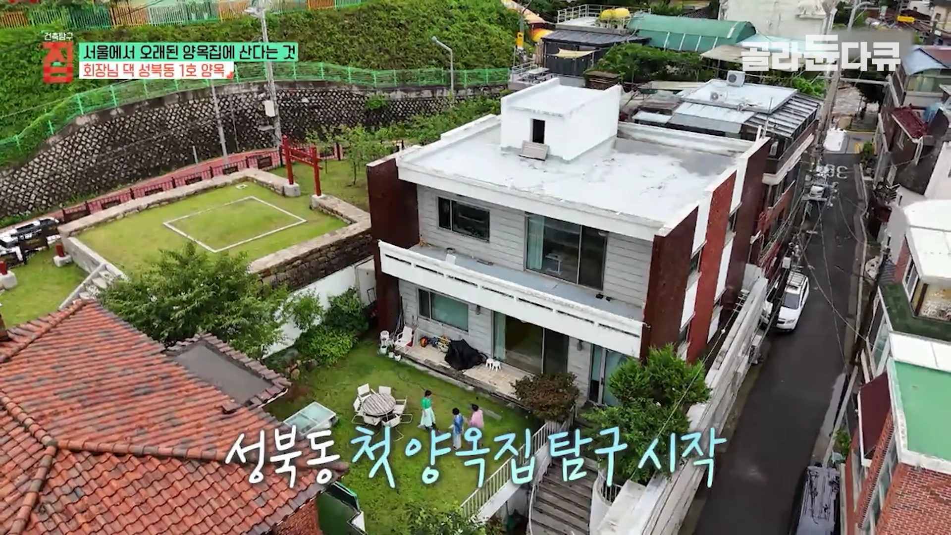 서울 성북동 주택가에 자리한 2층짜리 현대식 양옥집을 공중에서 내려다본 모습으로, 옆에는 선잠단지 유적지와 작은 정원이 보입니다.