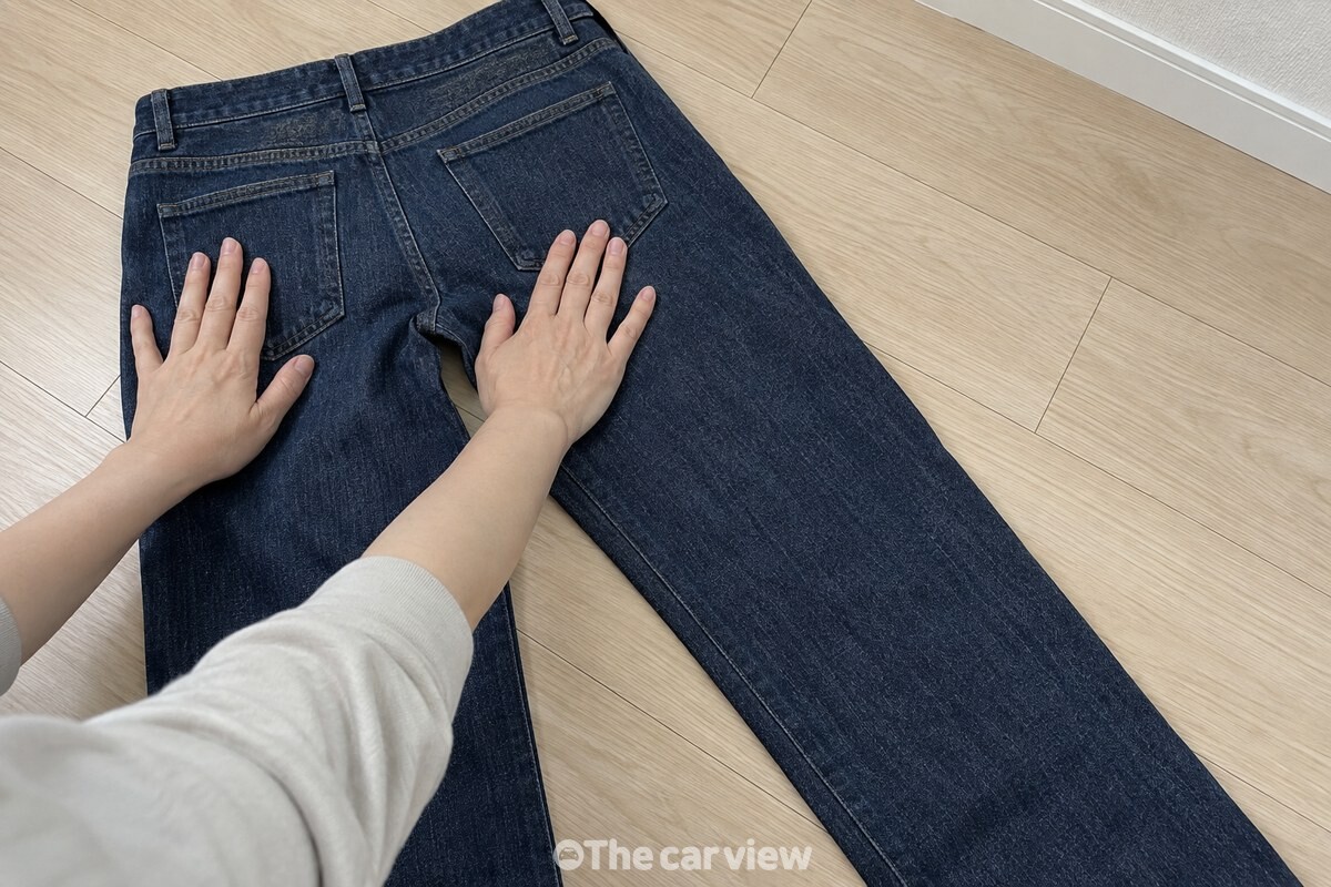평평한 바닥에서 청바지의 양쪽 옆선을 맞춰 펴는 손. / 기사 이해를 돕기 위한 생성형 이미지