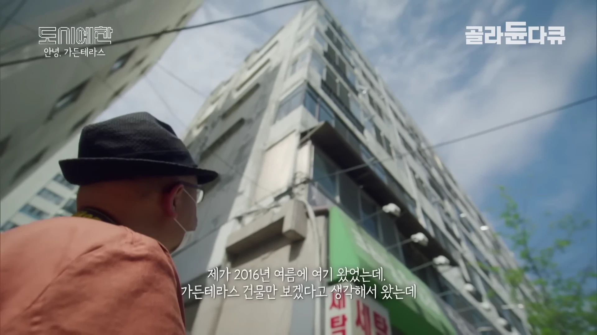 모자를 쓴 남성이 아래에서 위를 올려다보며 가든테라스 건물을 바라보고 있는 모습