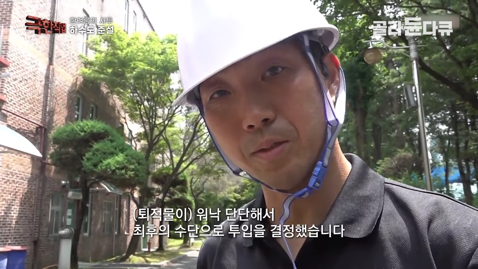 흰 안전모를 쓴 작업자가 야외 현장에서 카메라를 응시하며 인터뷰하고 있다.