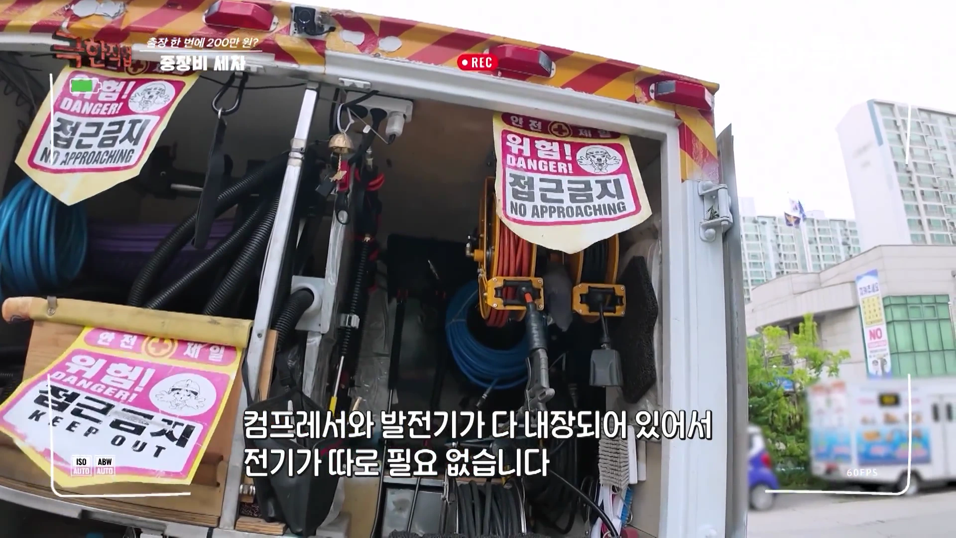 출장 세차용 트럭 적재함 내부 모습으로, 고압 세척기 호스와 스팀 건, 각종 공구가 수납되어 있고 출입문에는 위험 접근 금지 표지판이 부착되어 있다.