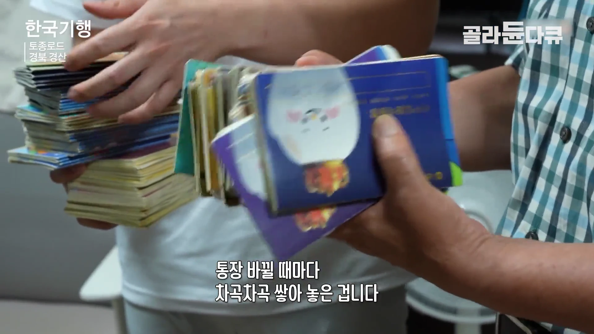 두 사람이 손에 수많은 금융 기관 통장을 뭉치로 들고 보여주고 있는 모습