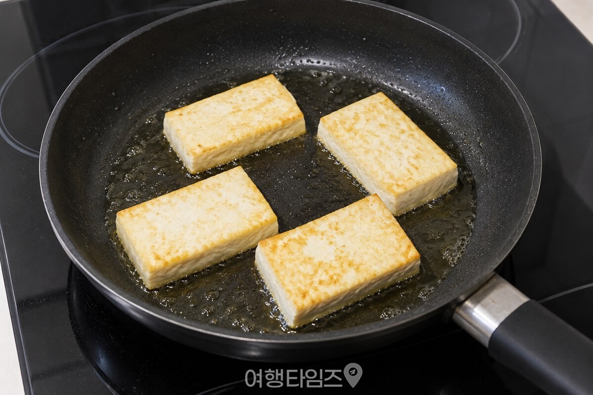 기름을 두른 팬에서 두부 한쪽 면이 노릇하게 익고 있다. / 기사 이해를 돕기 위한 생성형 이미지