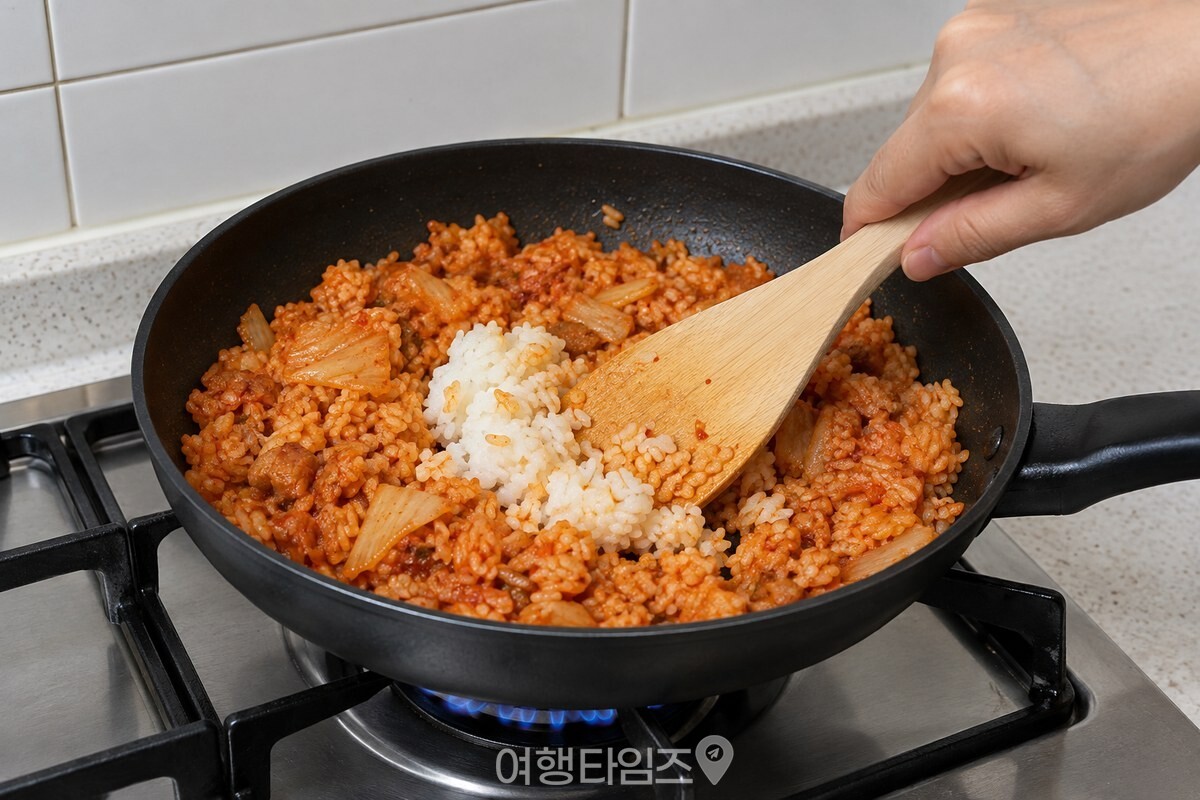 팬에 넣은 찬밥 덩어리를 주걱으로 눌러 풀며 김치와 섞는 모습. / 기사 이해를 돕기 위한 생성형 이미지