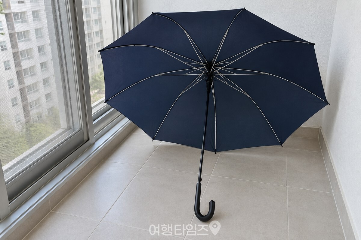 그늘진 베란다에서 펼친 우산을 손잡이가 아래로 향하게 말리는 모습. / 기사 이해를 돕기 위한 생성형 이미지