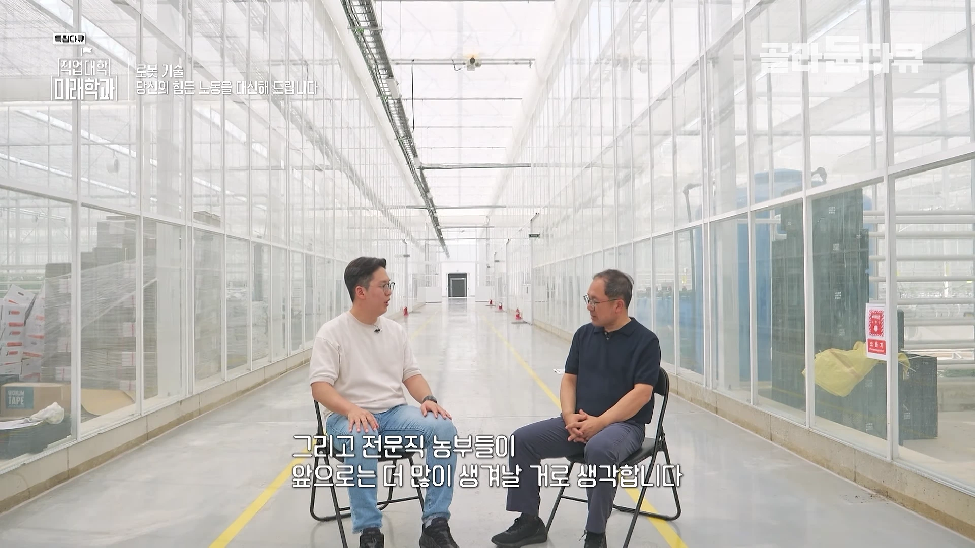 투명한 벽으로 둘러싸인 넓고 깔끔한 스마트팜 내부에서 두 남성이 의자에 앉아 인터뷰를 하고 있다.
