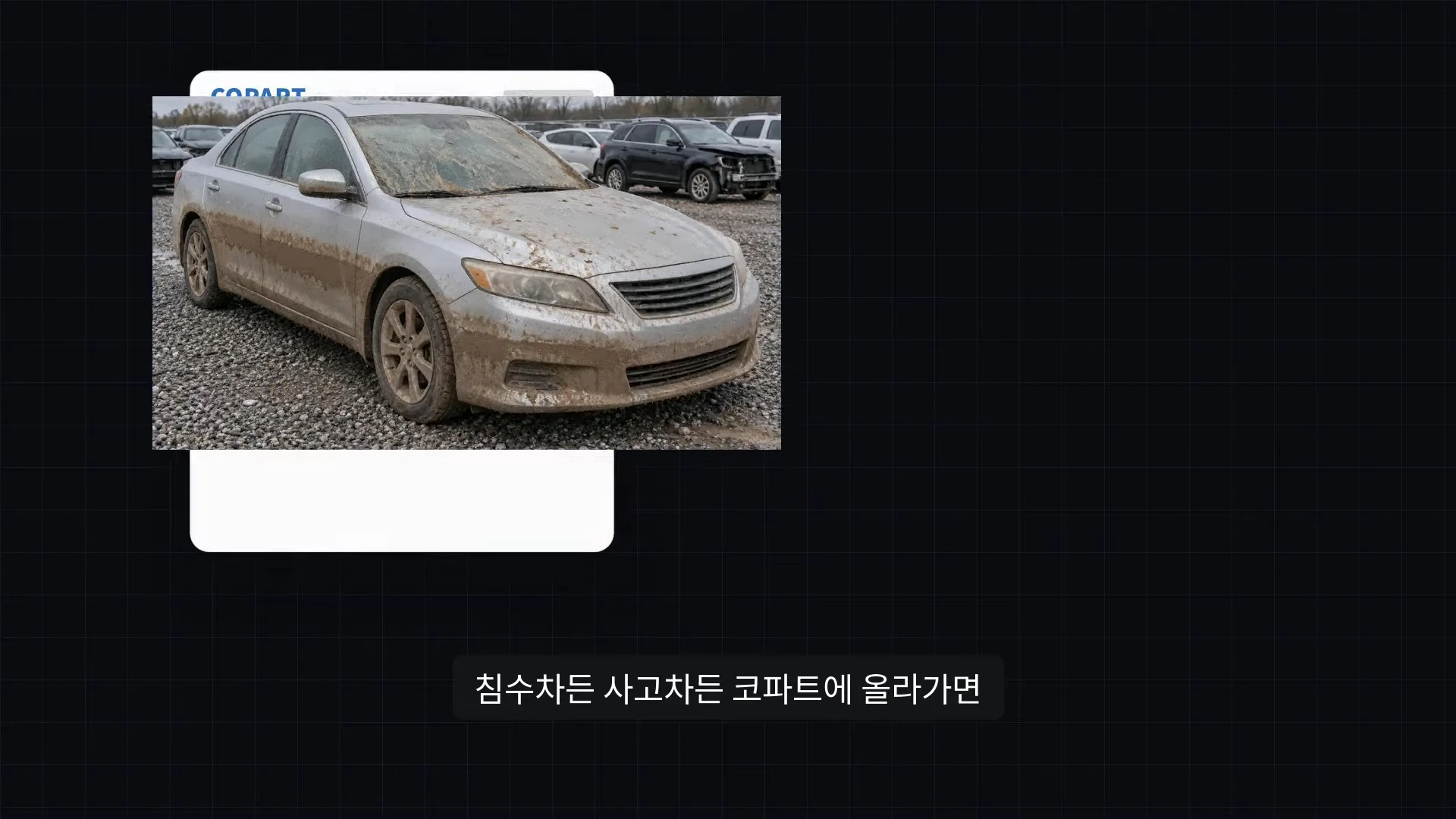 진흙이 묻은 채 야외 주차장에 세워져 있는 은색 승용차와 배경에 보이는 여러 대의 폐차들