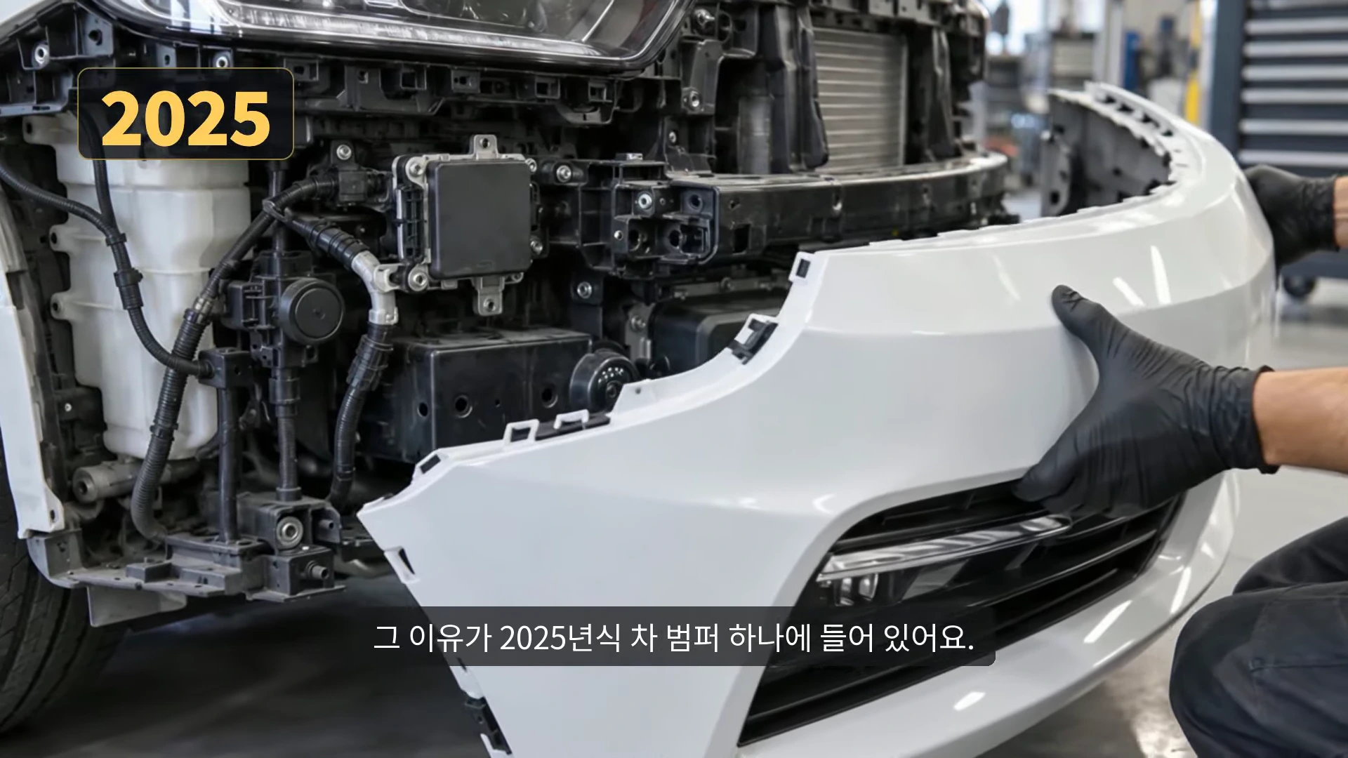 2025년형 차량의 앞 범퍼가 분리되어 내부의 복잡한 센서와 전자 장비들이 드러난 모습이며, 검은 장갑을 낀 손이 범퍼를 잡고 있고 좌측 상단에는 '2025'라는 노란색 텍스트가 표시되어 있습니다.