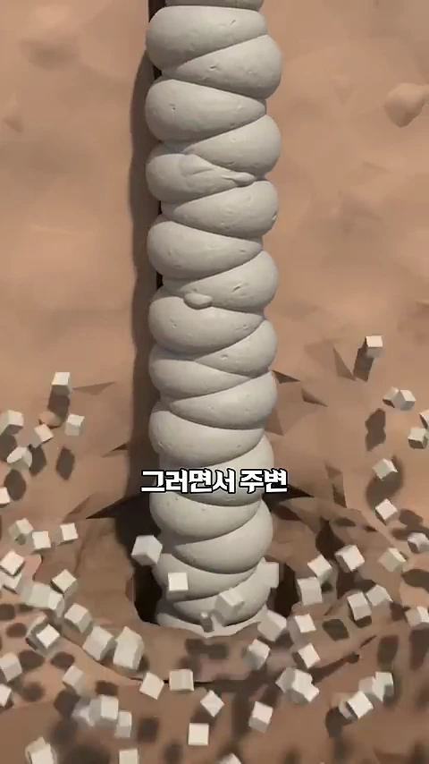 지면 아래로 길쭉한 원통형의 회색 구조물이 세워져 있고 주변의 흙 알갱이들이 흩날리는 모습을 보여주는 3D 그래픽 영상