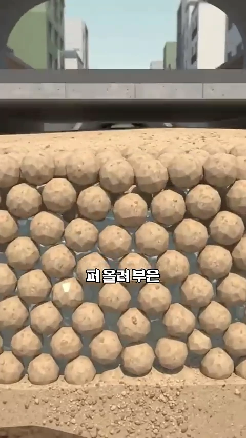 흙더미를 모형화한 그래픽으로 다각형 모양의 흙 알갱이들이 빽빽하게 채워져 있고 그 위로 도로 구조물이 보이는 모습
