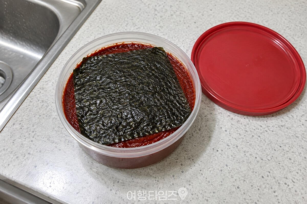 고추장 표면을 평평하게 고른 뒤 생김 한 장을 덮은 밀폐 용기 모습. / 기사 이해를 돕기 위한 생성형 이미지