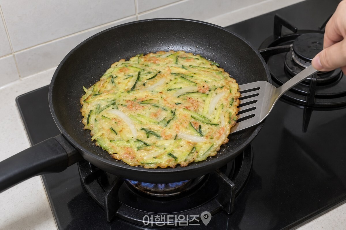 채 썬 호박과 양파를 넣은 새우가루 반죽을 팬에 얇게 펴 부치는 모습. / 기사 이해를 돕기 위한 생성형 이미지
