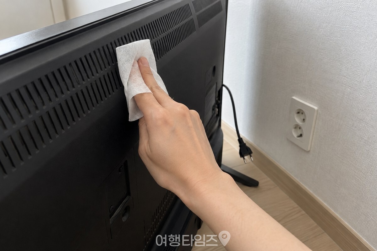 접은 마른 부직포를 검지와 중지에 감아 TV 뒷면을 위에서 아래로 닦는 모습. / 기사 이해를 돕기 위한 생성형 이미지