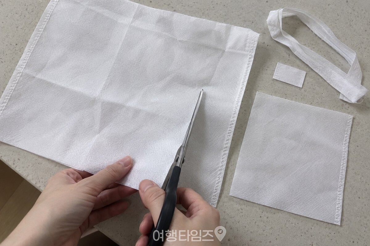 손잡이와 라벨을 뗀 흰 부직포 가방을 손바닥 크기 조각으로 자른 모습. / 기사 이해를 돕기 위한 생성형 이미지