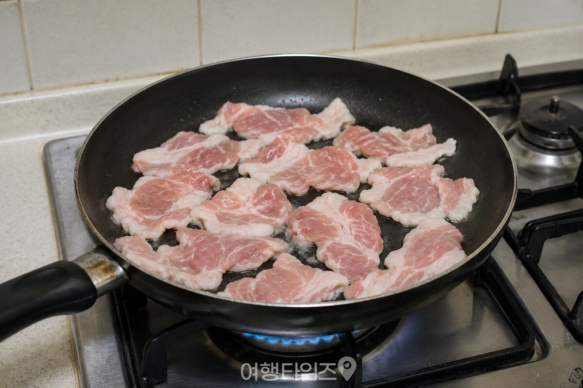 넓은 팬에 얇게 썬 돼지고기를 펼쳐 처음 익히는 장면 / 기사 이해를 돕기 위한 생성형 이미지
