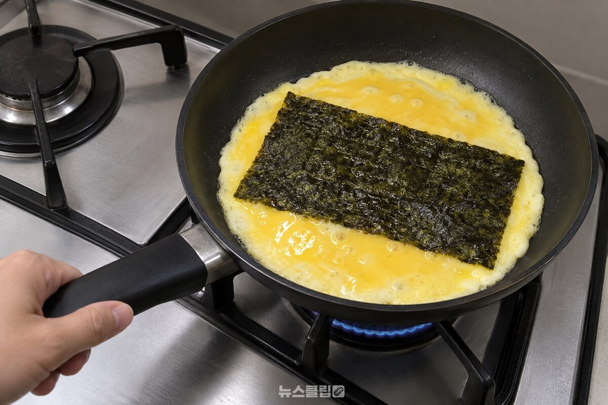 중약불의 팬에서 가장자리가 익은 계란물 위에 조미김 한 장을 올린 모습. / 기사 이해를 돕기 위한 생성형 이미지