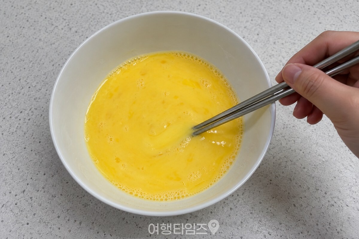 우유를 넣은 묽은 계란물을 흰 그릇에서 젓가락으로 섞는 모습. / 기사 이해를 돕기 위한 생성형 이미지