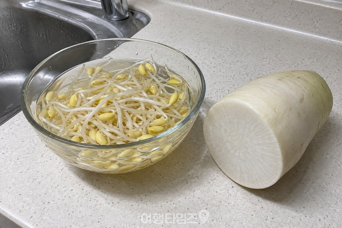 맑은 물에 담긴 콩나물과 옆에 놓인 단면 무가 국물 재료의 차이를 보여 준다. / 기사 이해를 돕기 위한 생성형 이미지