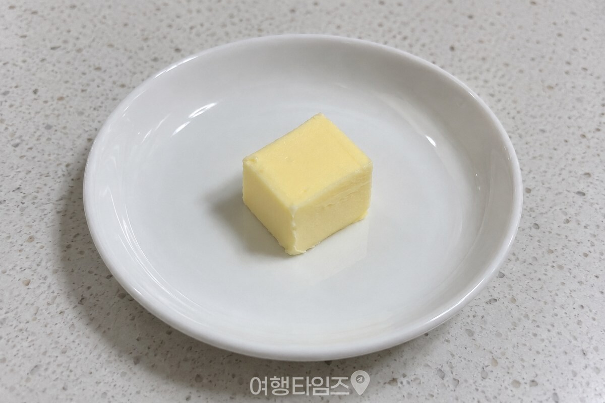 가로세로 약 2cm로 자른 버터 한 조각이 깨끗한 작은 접시에 놓여 있다. / 기사 이해를 돕기 위한 생성형 이미지