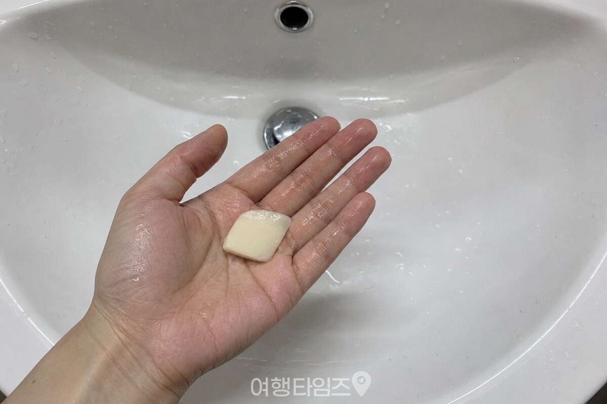 젖은 작은 비누 조각이 세면대 안쪽의 깨끗한 손바닥 위에 놓여 있다. / 기사 이해를 돕기 위한 생성형 이미지