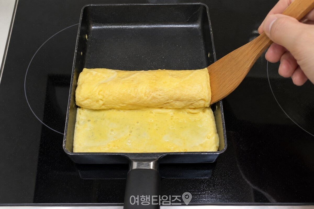 반쯤 익은 계란을 사각 팬 한쪽에서 천천히 말아 올리는 모습. / 기사 이해를 돕기 위한 생성형 이미지