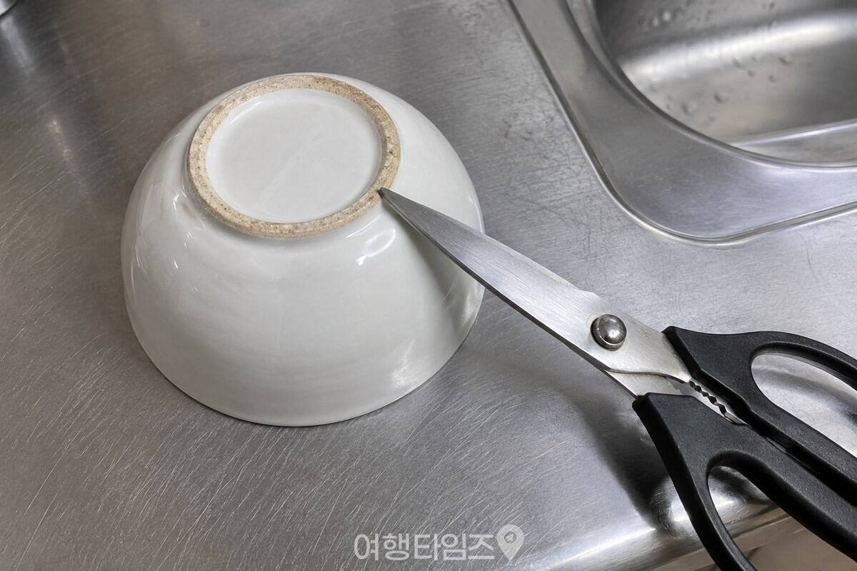 뒤집은 도자기 밥그릇 바닥의 거친 테두리에 주방 가위 한쪽 날을 대고 있는 모습. / 기사 이해를 돕기 위한 생성형 이미지