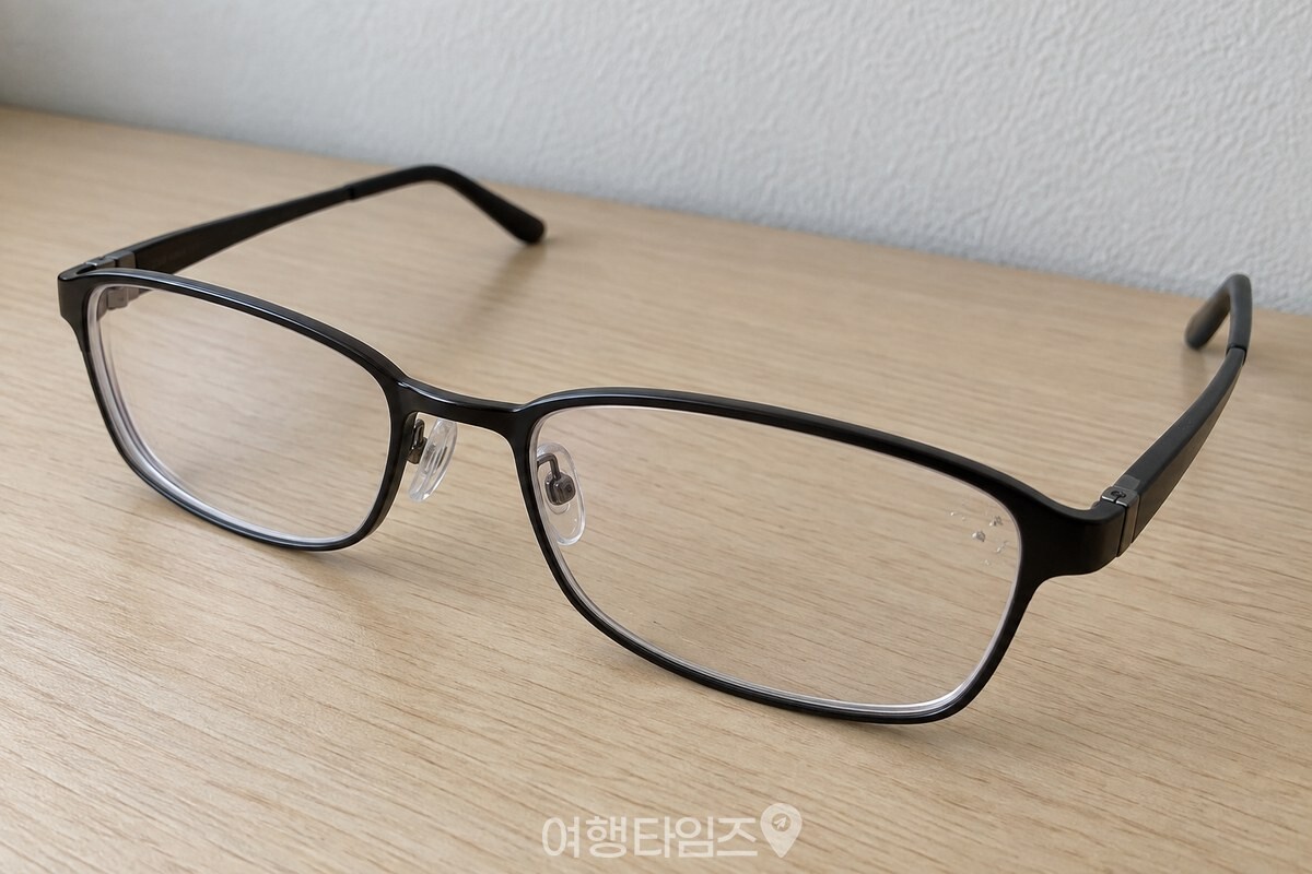 검은 테 안경 렌즈 한쪽에만 작은 먼지 알갱이가 보이는 근접 장면. / 기사 이해를 돕기 위한 생성형 이미지