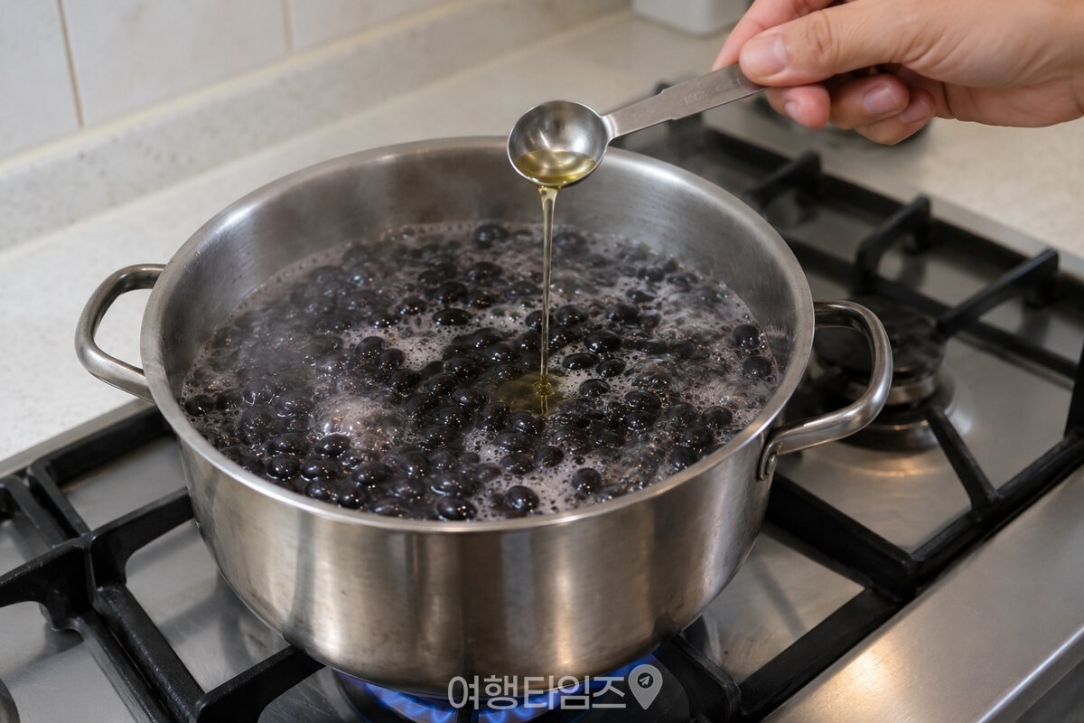 끓는 콩 냄비에 계량스푼으로 식용유를 넣는 손의 모습. / 기사 이해를 돕기 위한 생성형 이미지