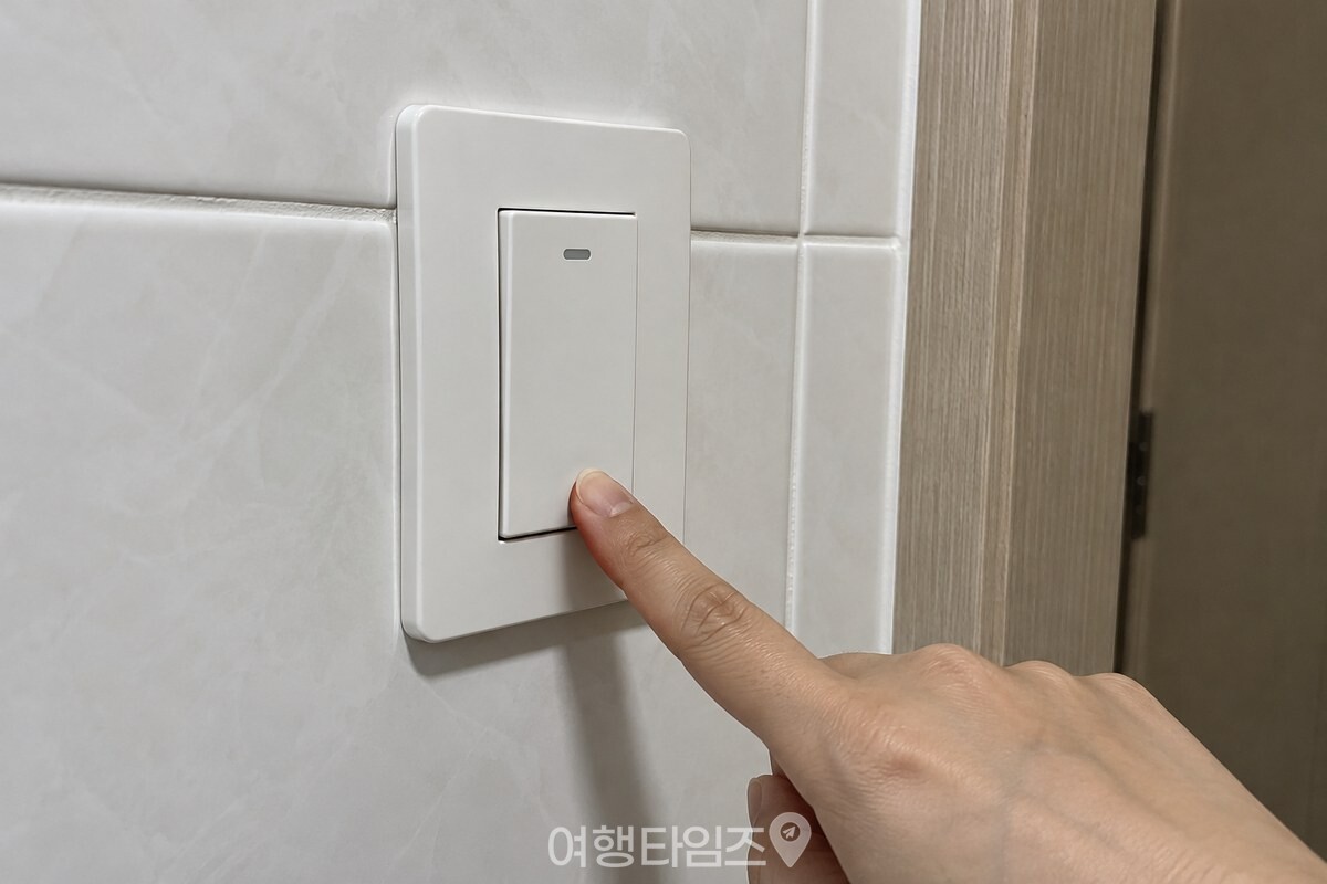 환풍기 스위치를 내린 욕실 벽면의 스위치와 꺼진 표시를 확인하는 모습 / 기사 이해를 돕기 위한 생성형 이미지