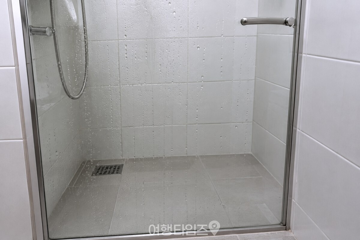 깨끗한 욕실 유리문에 물방울이 아래로 길게 흘러내리는 모습. / 기사 이해를 돕기 위한 생성형 이미지