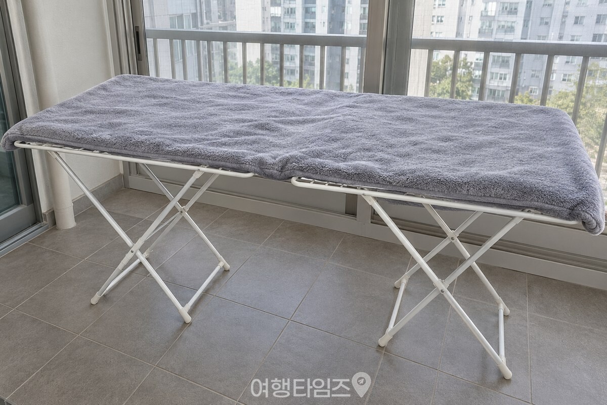 극세사 이불이 두 개의 접이식 건조대 윗면에 평평하게 펼쳐져 있다. / 기사 이해를 돕기 위한 생성형 이미지