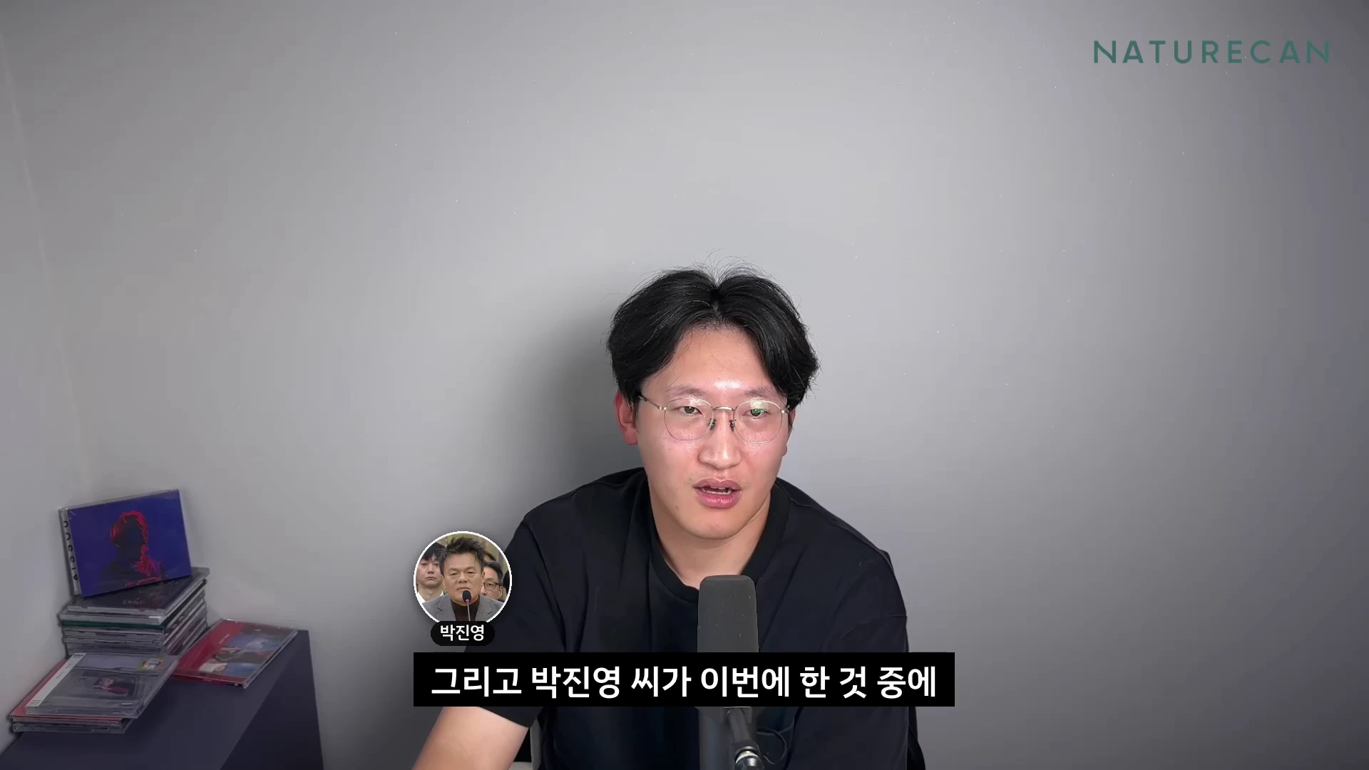 안경을 쓴 한 남성이 마이크 앞에서 이야기하고 있으며 화면 하단에는 박진영의 모습이 담긴 작은 원형 자막이 떠 있다.