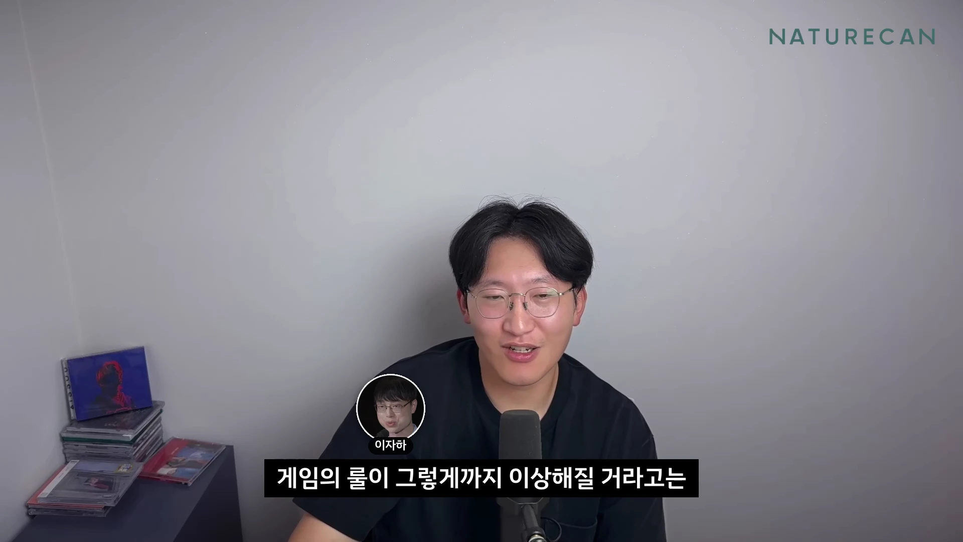 안경을 쓴 남성이 마이크 앞에 앉아 이야기하는 모습이 담긴 영상 캡처 화면이며, 하단에는 '게임의 룰이 그렇게까지 이상해질 거라고는'이라는 한국어 자막이 표시되어 있습니다.