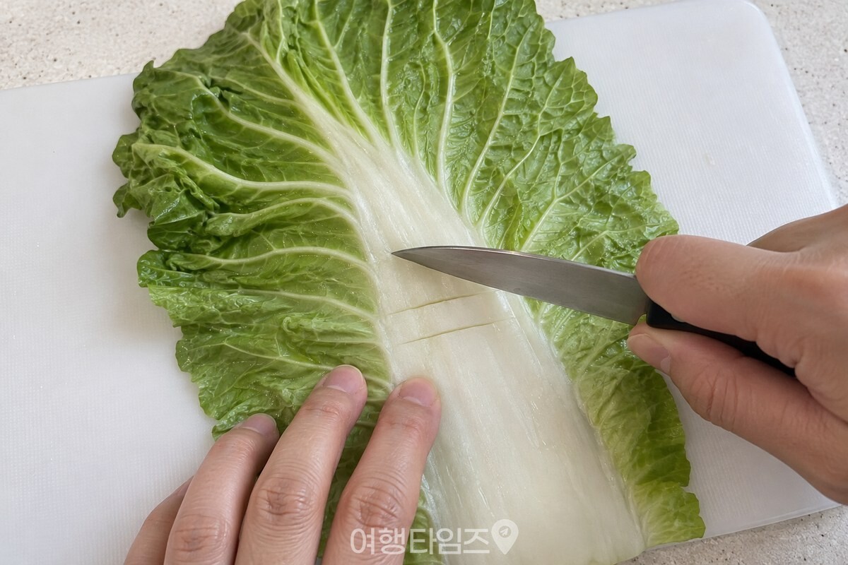 씻은 배춧잎의 두꺼운 흰 줄기에 얕은 칼집을 넣고 있다. / 기사 이해를 돕기 위한 생성형 이미지